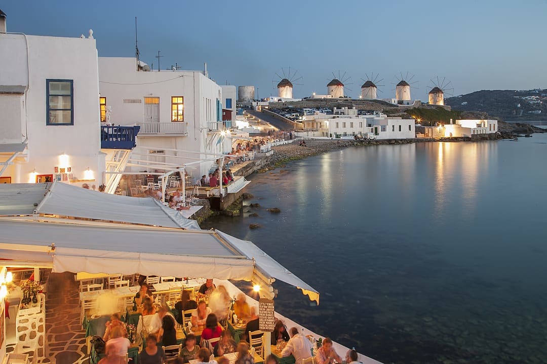 Scenic evening view of Little Venice in Mykonos, Greece, with iconic windmills and waterfront dining