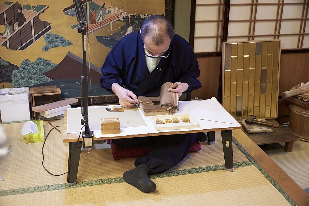 Japanese artisan applying gold leaf by hand in a traditional workshop in Kanazawa, Japan