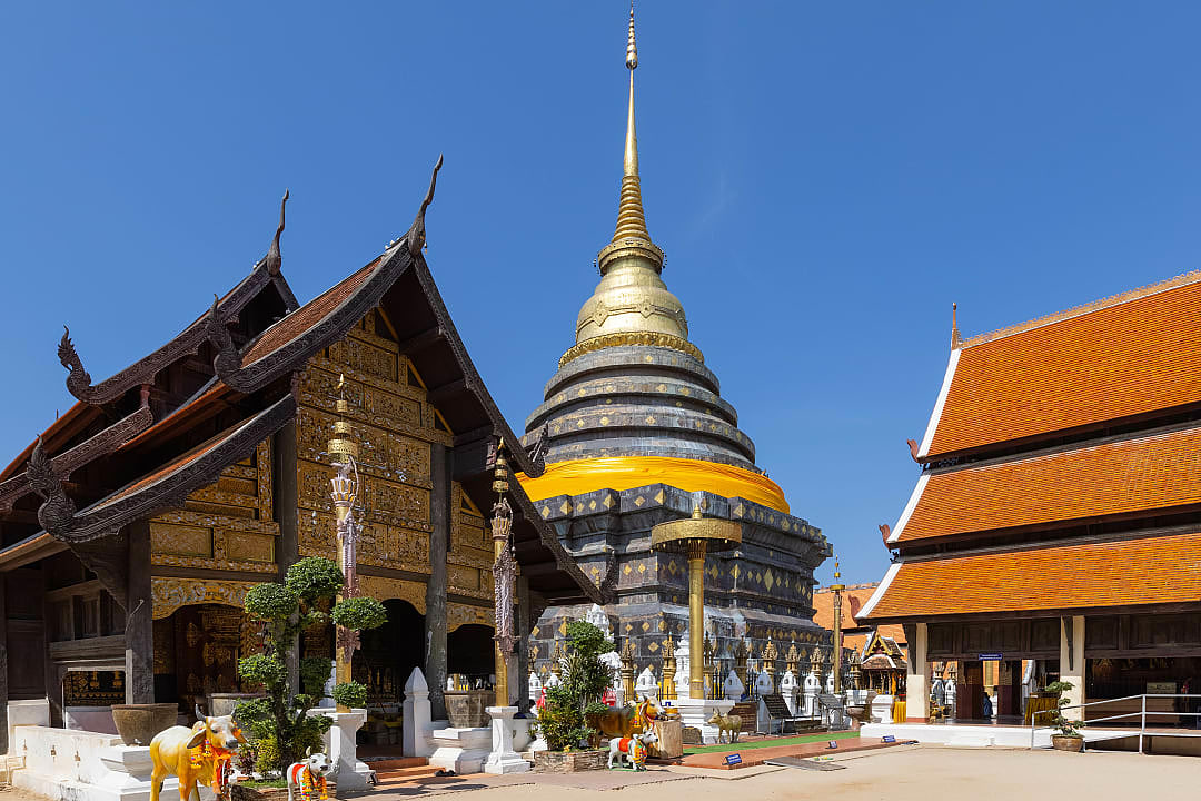 Golden stupa and ornate wooden temple buildings at Wat Phra That Lampang Luang, Thailand