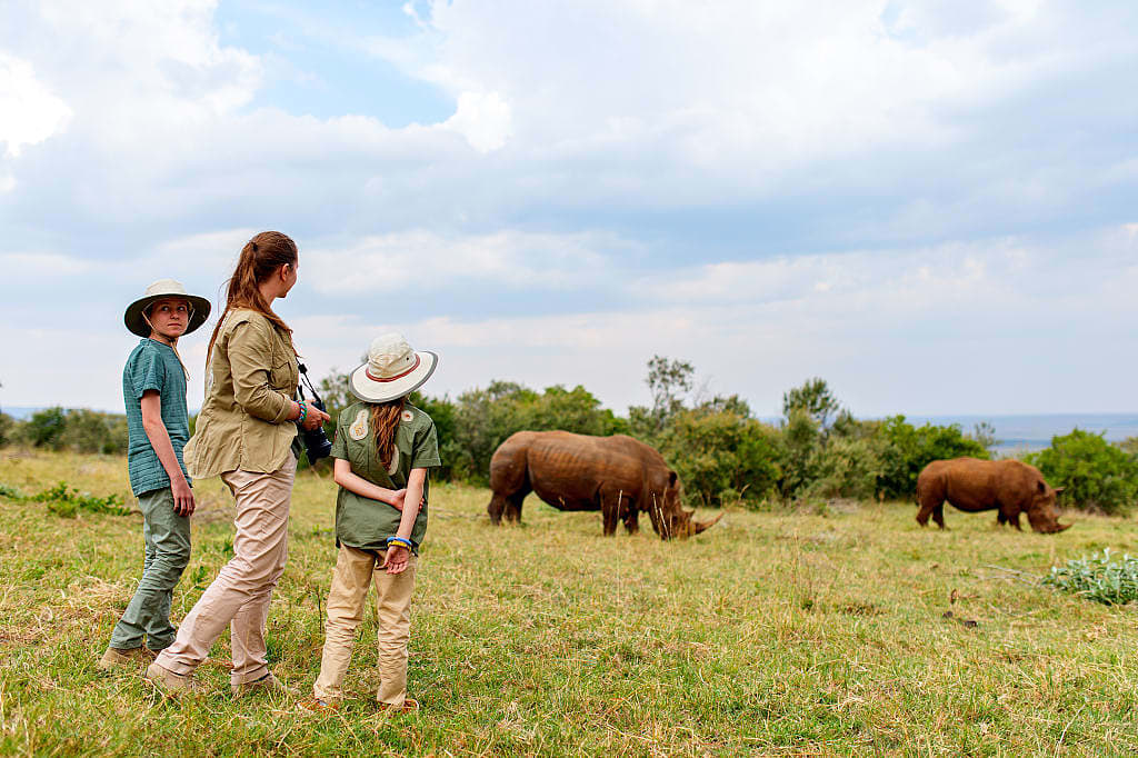 Family on walking safari in Kenya observing rhinos