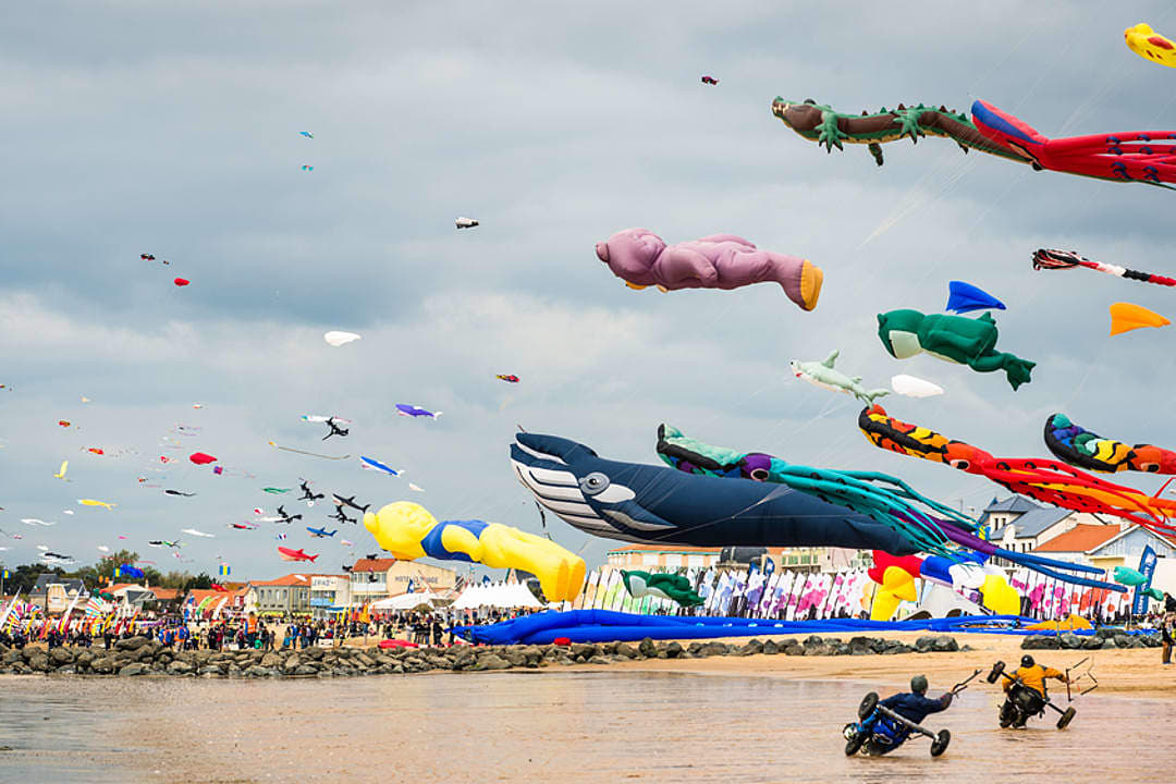 Colorful kites flying in the blue sky over sandy Châtelaillon-Plage during the International Kite and Wind Festival in La Rochelle, France