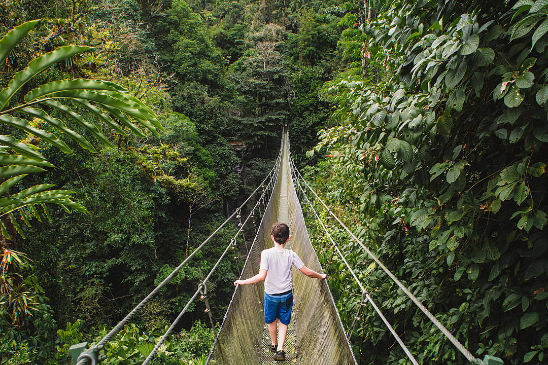 Child crossing hanging suspension bridge in the jungle of Costa Rica