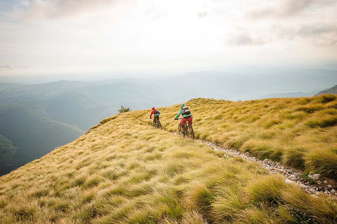 Two mountain bikers riding on grassy mountain ridge