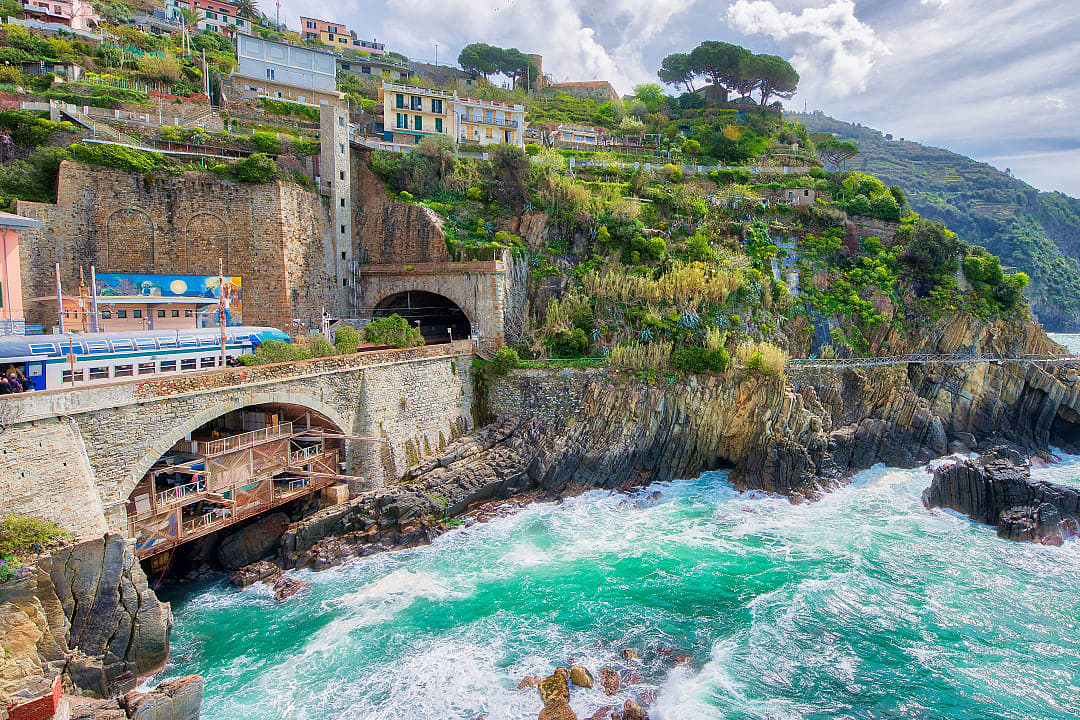Train traveling through different villages in Cinque Terre, Italy.