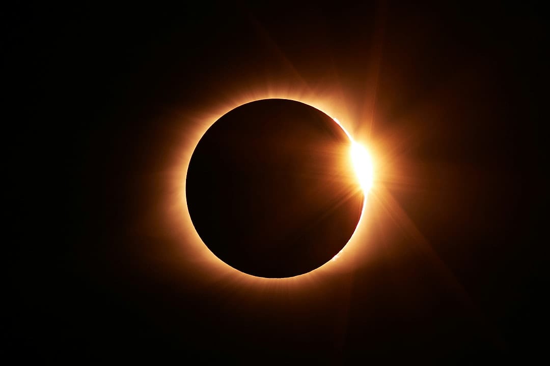 Total solar eclipse with the sun’s corona and diamond ring effect glowing behind the moon in a dark sky