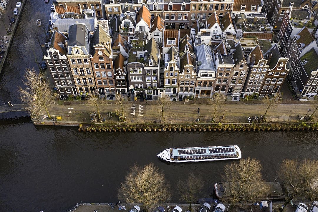 A boat cruises through Amsterdam’s canals, lined with historic buildings.