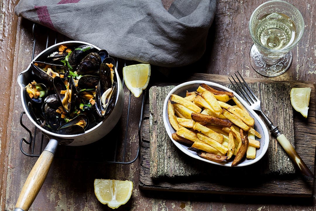 Moules Frites, a classic Belgian dish with mussels, cooked in a flavorful broth and served with crispy fries.