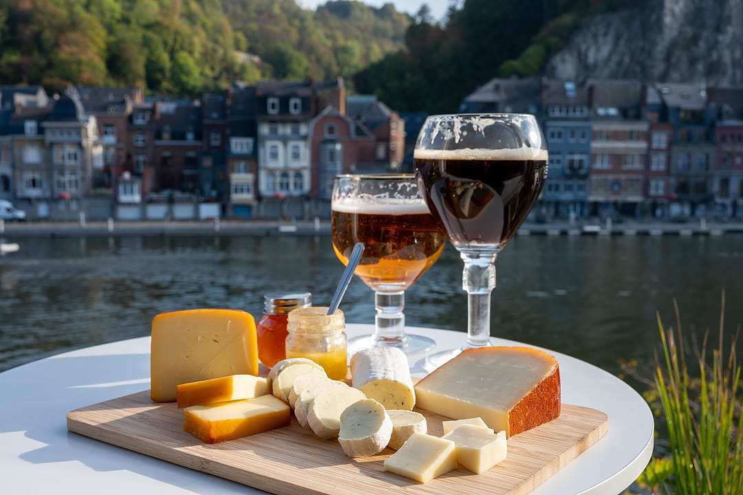 Two glasses of beer and cheese board by a river.