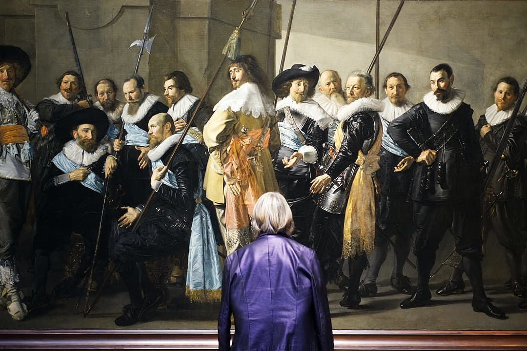 A visitor admires a Dutch Golden Age painting at Rijksmuseum.