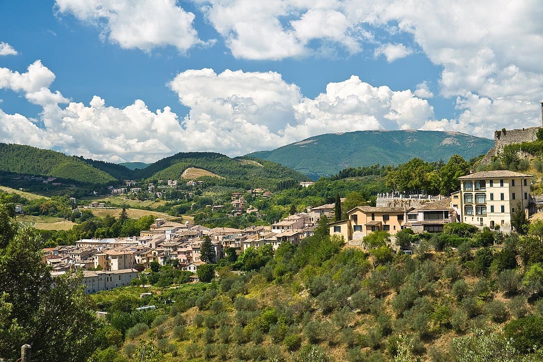 Scenic view of Foligno, Italy, surrounded by green hills and olive trees under a blue sky