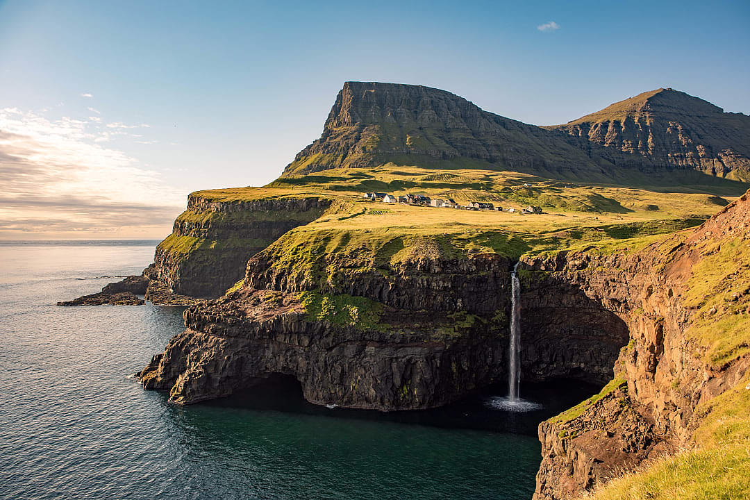 Múlafossur Waterfall cascading from sea cliffs into the Atlantic Ocean at Gásadalur village, Vágar, Faroe Islands.