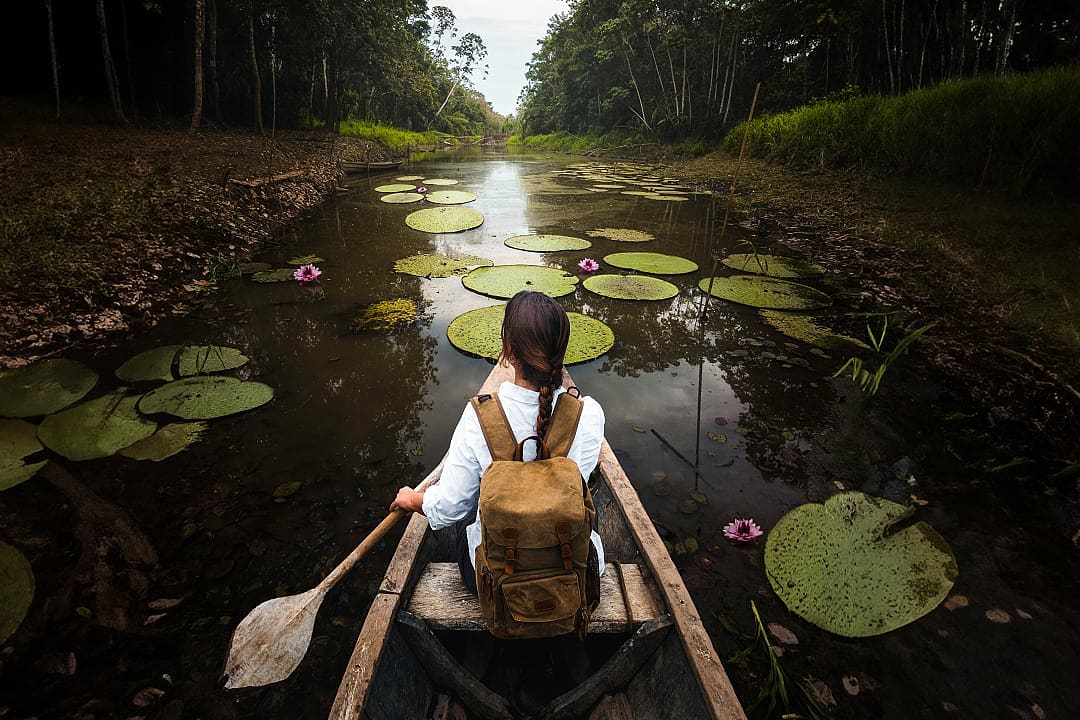 raveler canoeing among giant water lilies in the Amazon rainforest