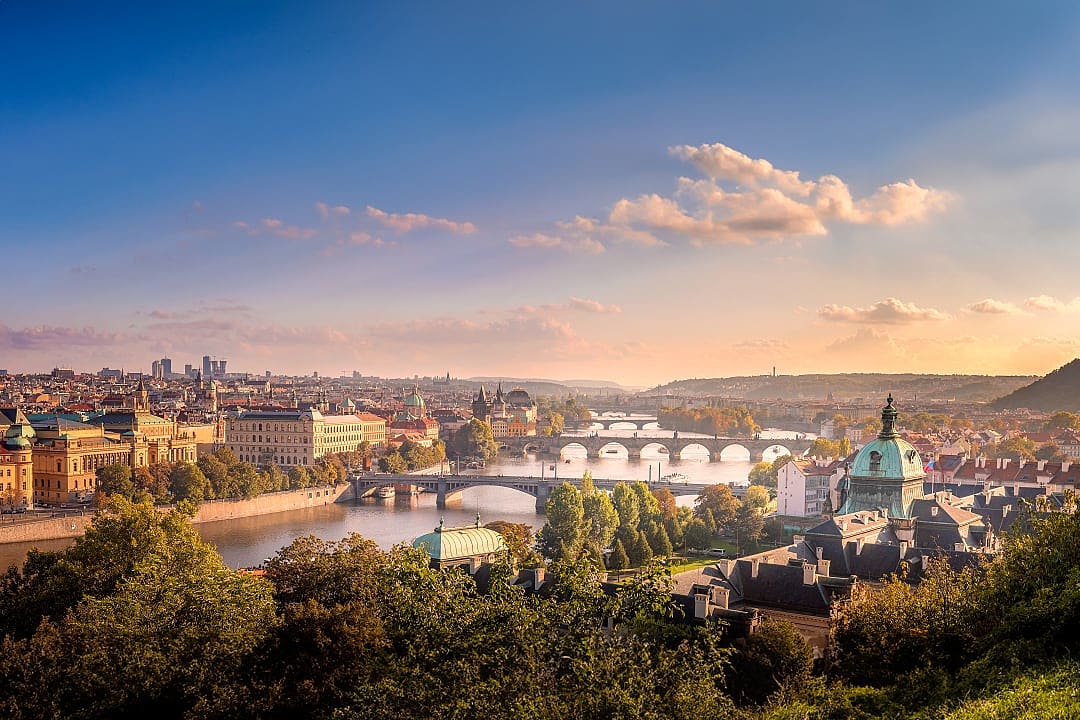 Scenic view of Prague at sunset with iconic bridges, the Vltava River, and historic architecture