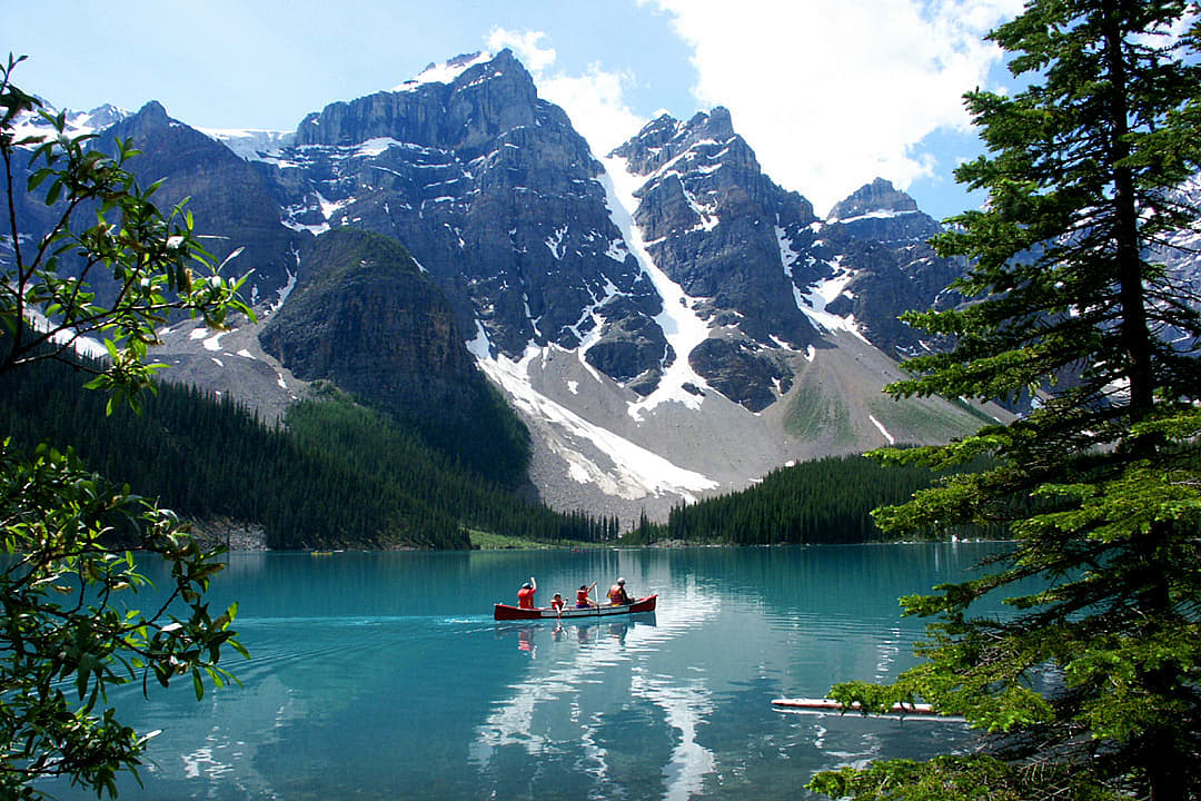 A canoe glides across Moraine Lake's turquoise waters.