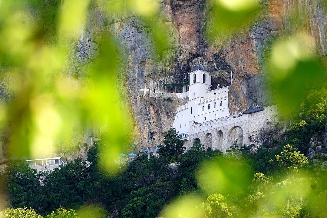White monastery complex built directly into a steep gray cliffside.