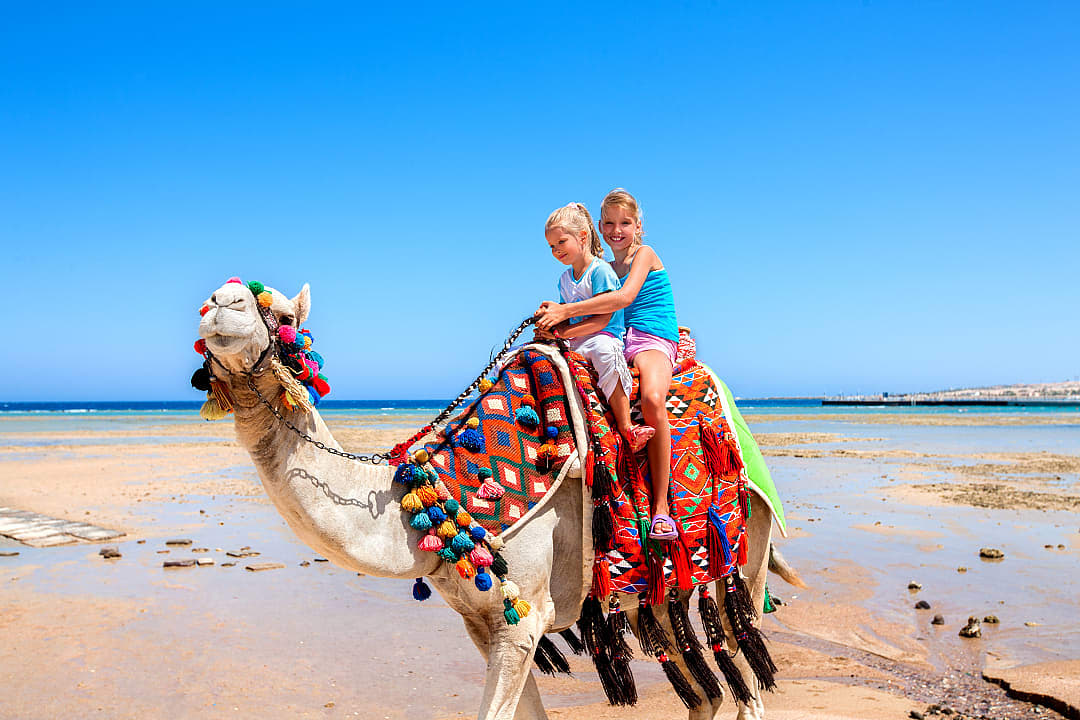 Sisters riding camel on the beach in Egypt