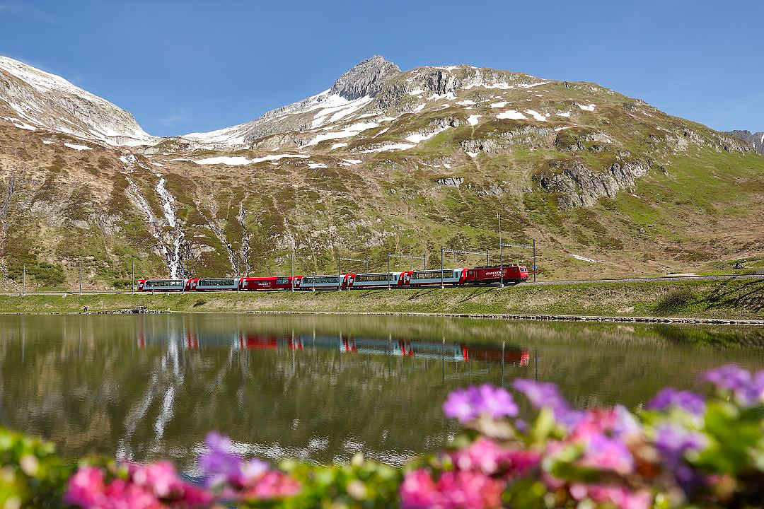 Glacier Express crossing Oberalp Lake with alpine peaks in the Swiss Alps