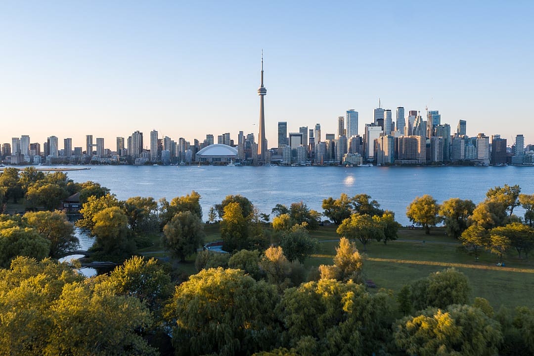 The Toronto skyline shines brightly across the water from the islands.