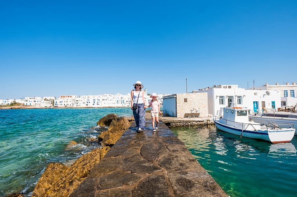 Mom and daughter walk along the embankment of Paros