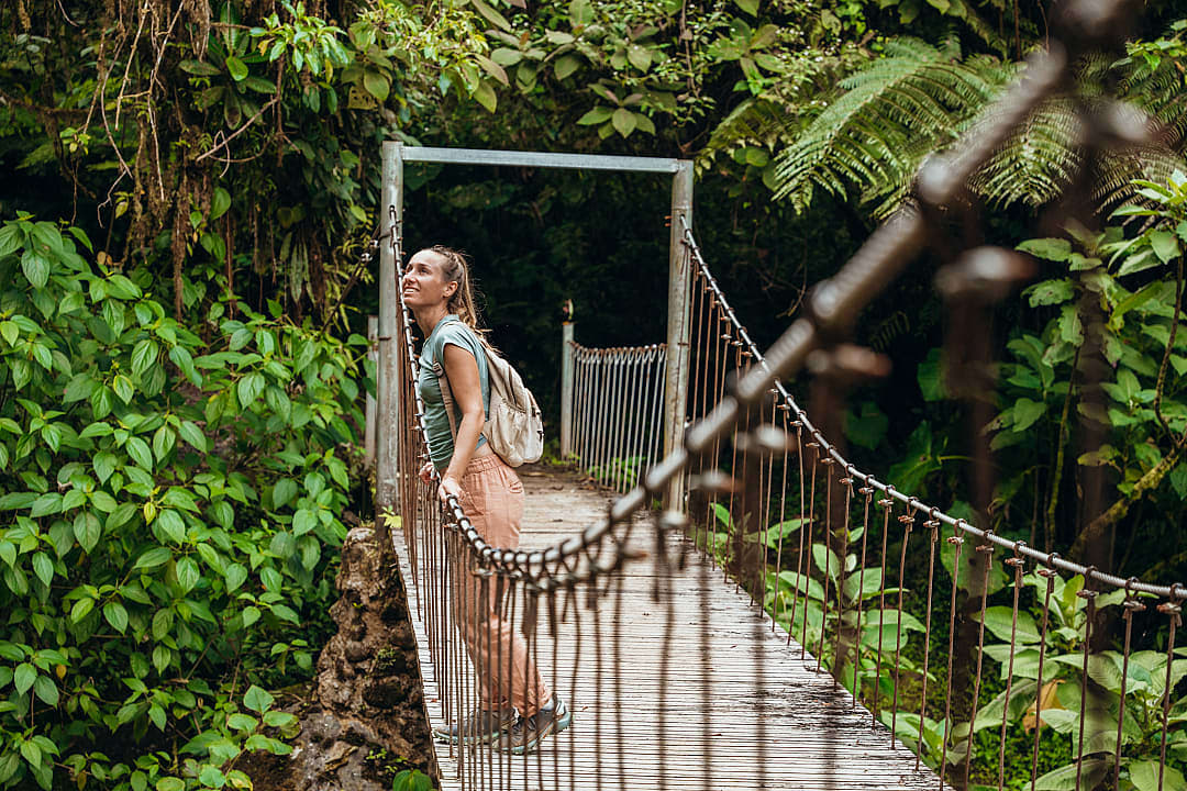 Woman standing on a suspension bridge surrounded by dense green cloud forest in Costa Rica.