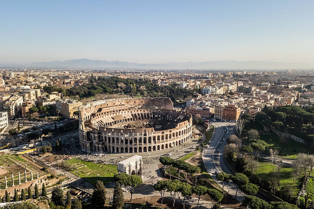 The Colosseum stands proudly in Rome, surrounded by historic cityscape views.