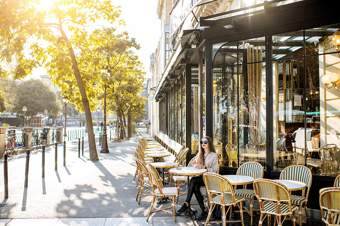 Woman sitting streetside at a cafe in the morning in Paris