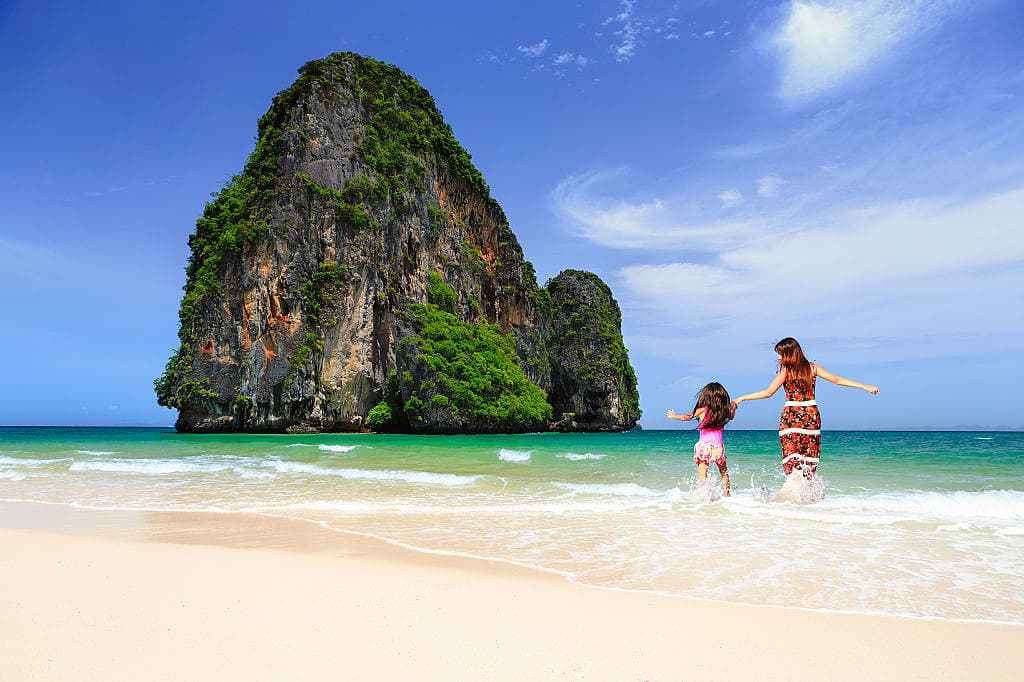 Mother and daughter running in the water on Railay beach in Krabi, Thailand
