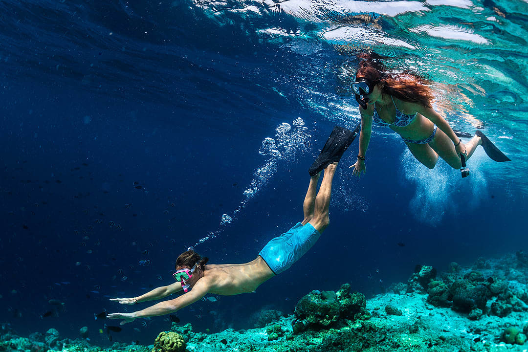 Couple snorkels through crystal-clear Maldivian waters, discovering vibrant marine life.