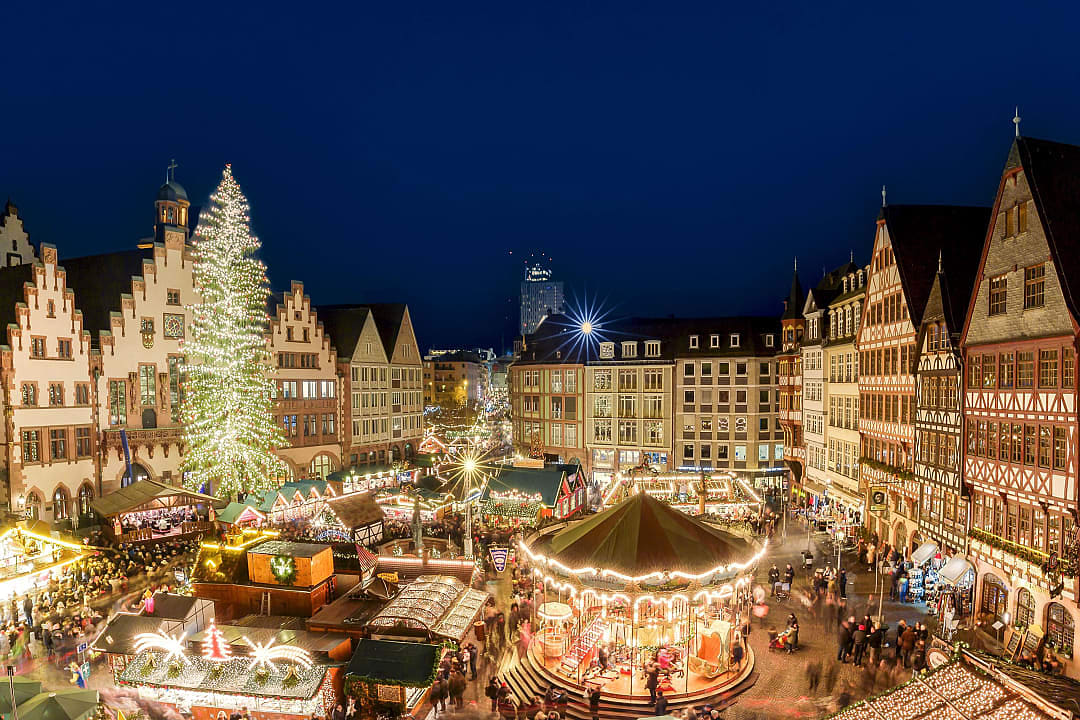 Frankfurt Christmas Market in Römerberg square, glowing with lights, stalls, a carousel, and tree at night