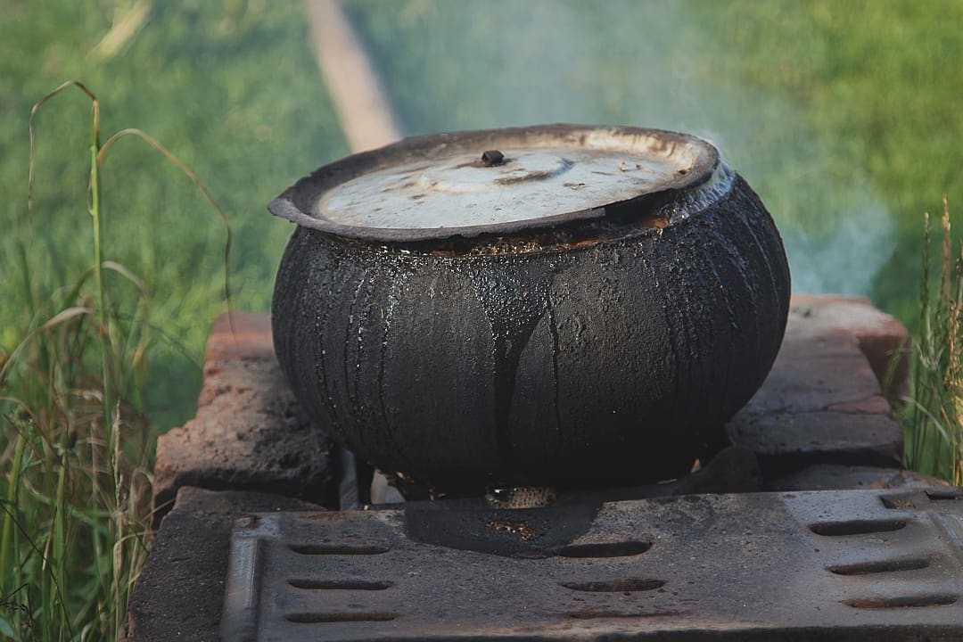 A traditional cast-iron pot, also known as a Potjie, used for cooking food outdoors.
