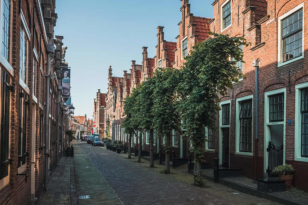 A narrow cobblestone street lined with traditional brick almshouses in Haarlem.
