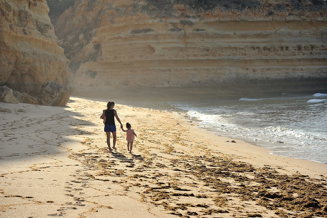 A family walking along a sun-kissed beach in the Algarve.