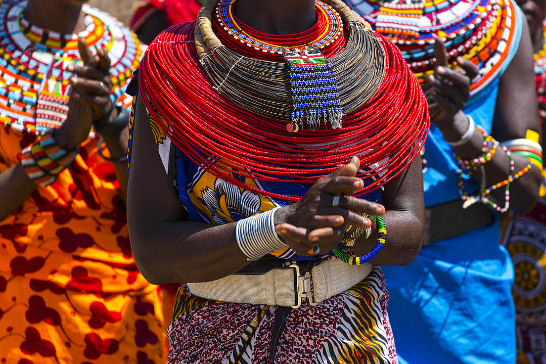 A group of people dressed in vibrant traditional attire adorned with colorful beadwork, symbolizing cultural heritage and community connection.