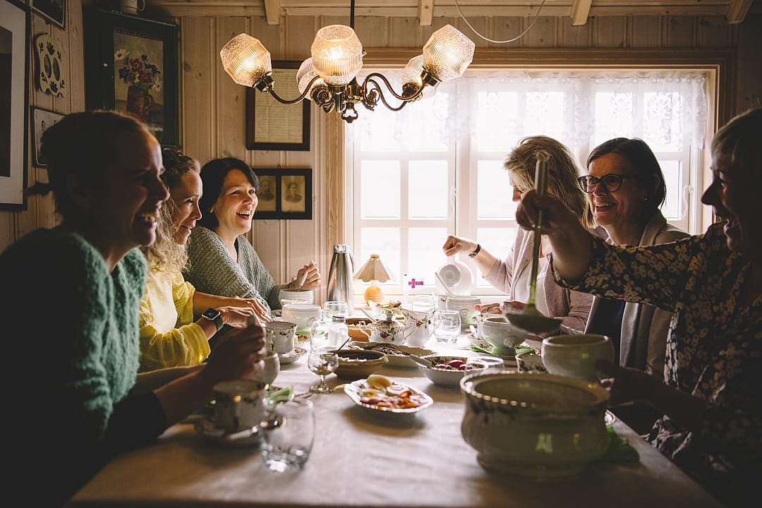 Group of people sharing a traditional Faroese meal inside a cozy home, representing the heimablídni dining experience in the Faroe Islands.
