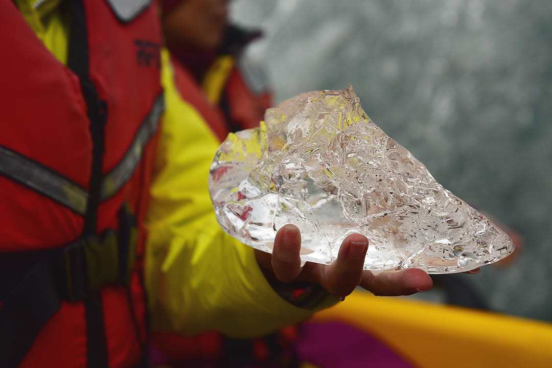 A guide holds a chunk of melting ice at the Tasman Lake, Aoraki Mount Cook National Park, New Zealand