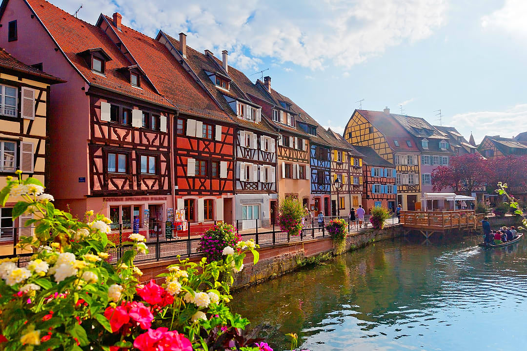 Traditional street in Alsace, featuring timbered houses and flowers, France.