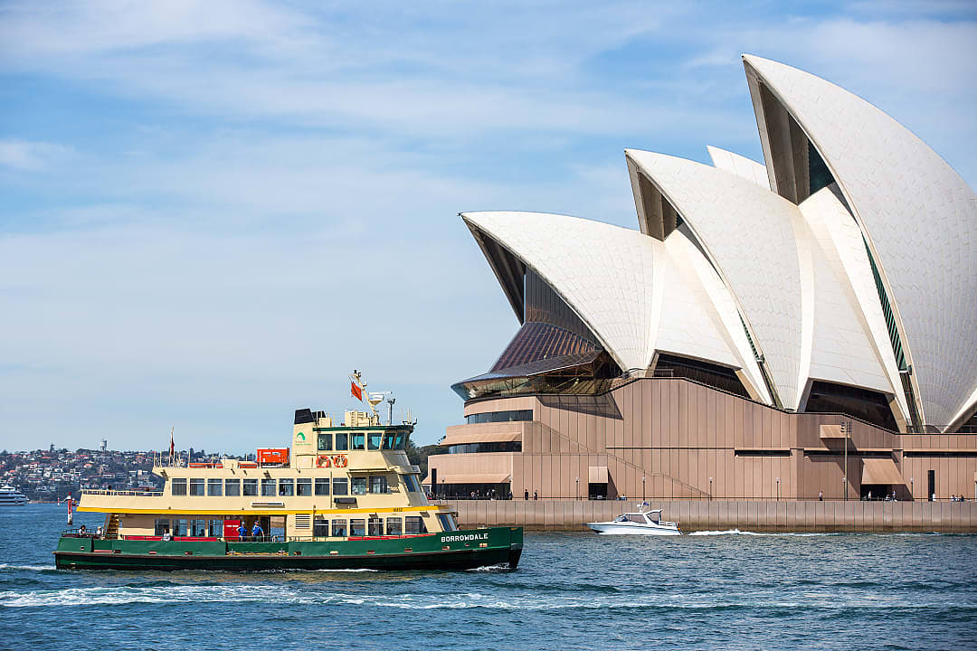 The iconic green and yellow ferry in Sydney, passing The Opera House.