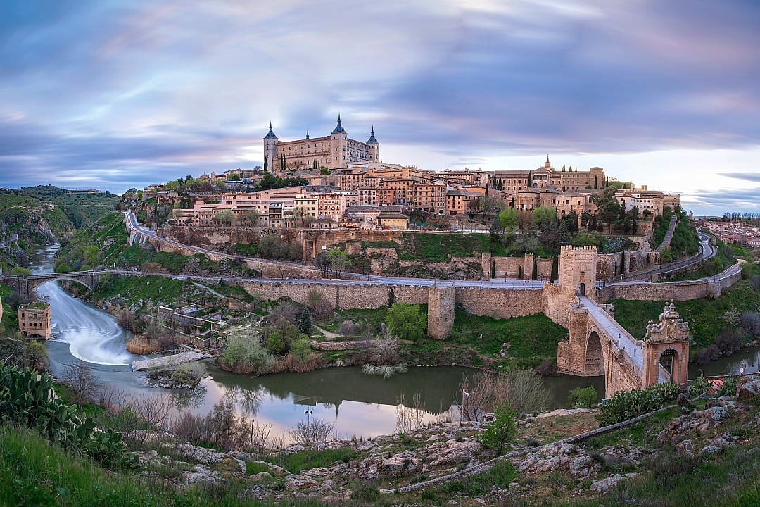 Panoramic view of Toledo, Spain, featuring the Alcázar and historic architecture overlooking the Tagus River