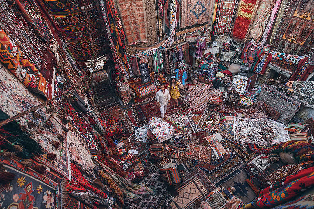 Couple in a colorful handmade carpets and textiles displayed in traditional souk shop