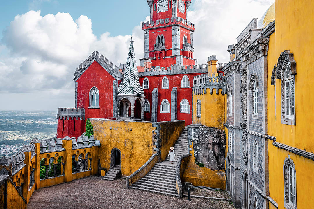Woman standing on the stairs at the colorful Pena Palace in Sintra, Portugal