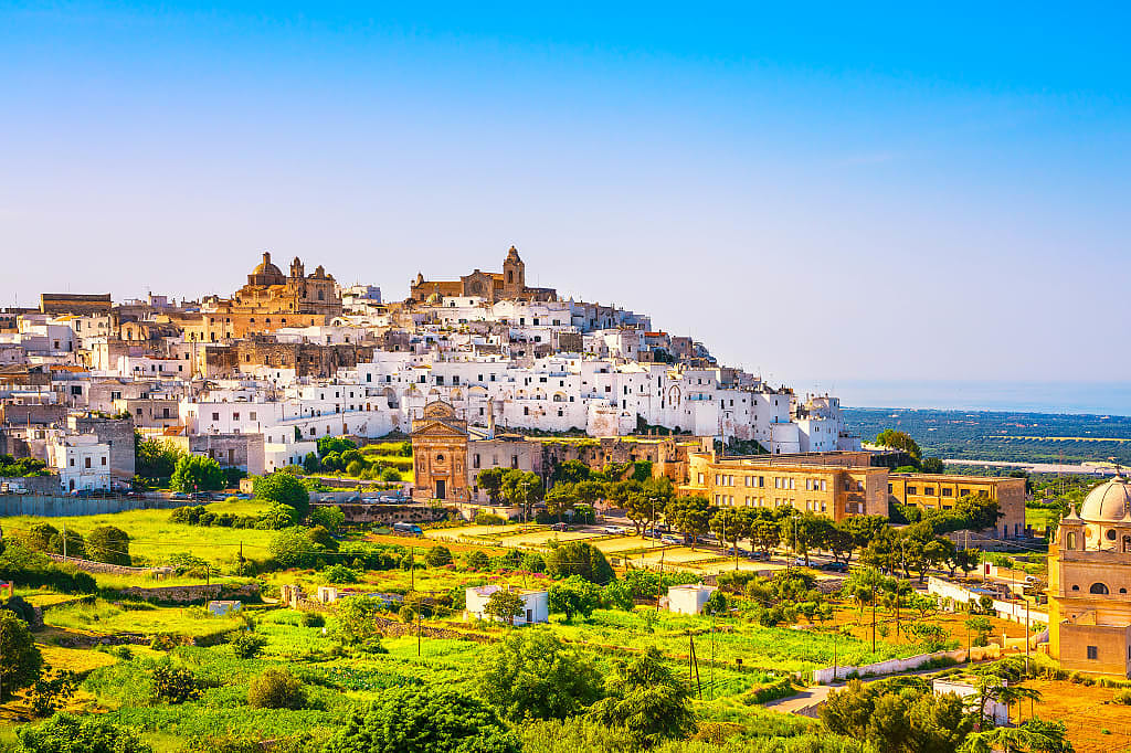 Whitewashed buildings of old town with church on the hill in Ostuni, Italy