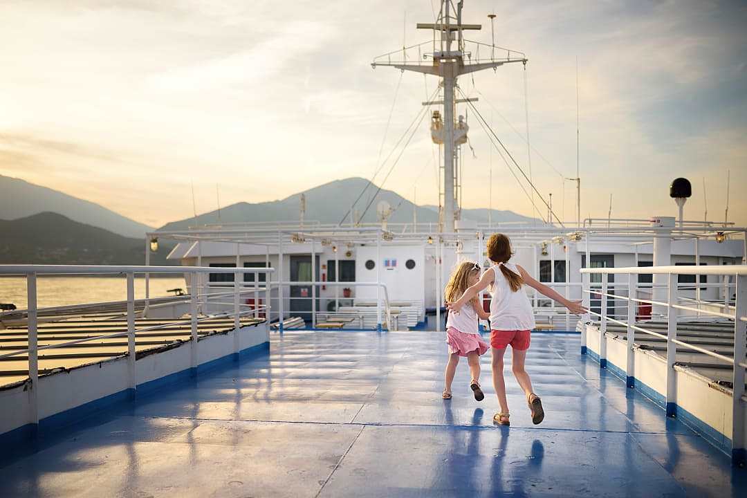 Two young children running on the deck of a ferry.