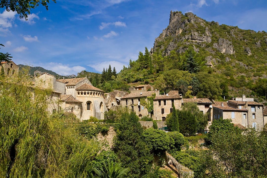Historic medieval village of Saint-Guilhem-le-Désert, France, surrounded by lush greenery and cliffs