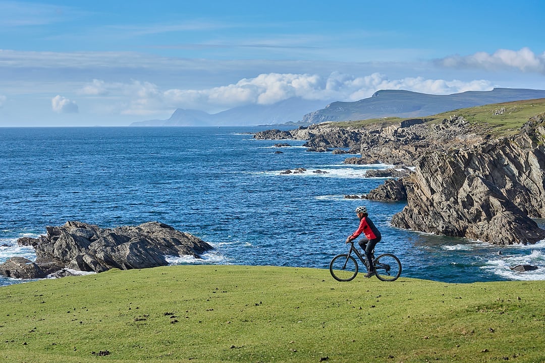 Senior woman cycling the cliffs of Achill island on the Wild Atlantic Way in Ireleand