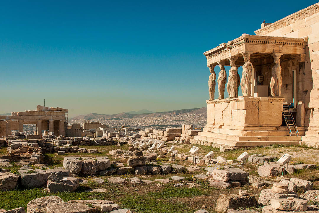 Caryatid porch of Erechtheion overlooking ancient ruins in Athens.