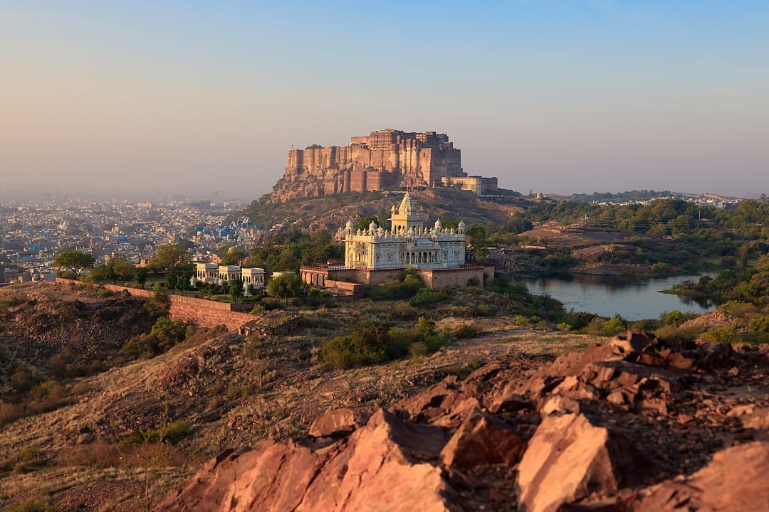 Majestic fort rises above blue city and marble memorial landscape.