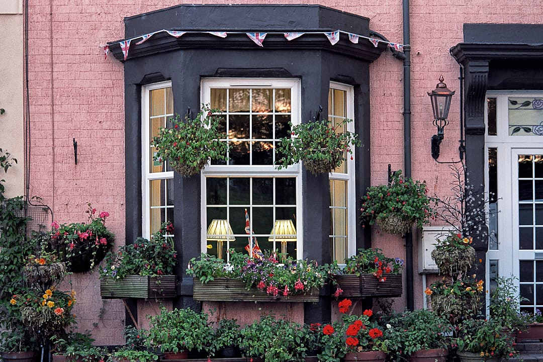 A traditional pink brick Bed and Breakfast exterior with a large bay window and flowering window boxes.