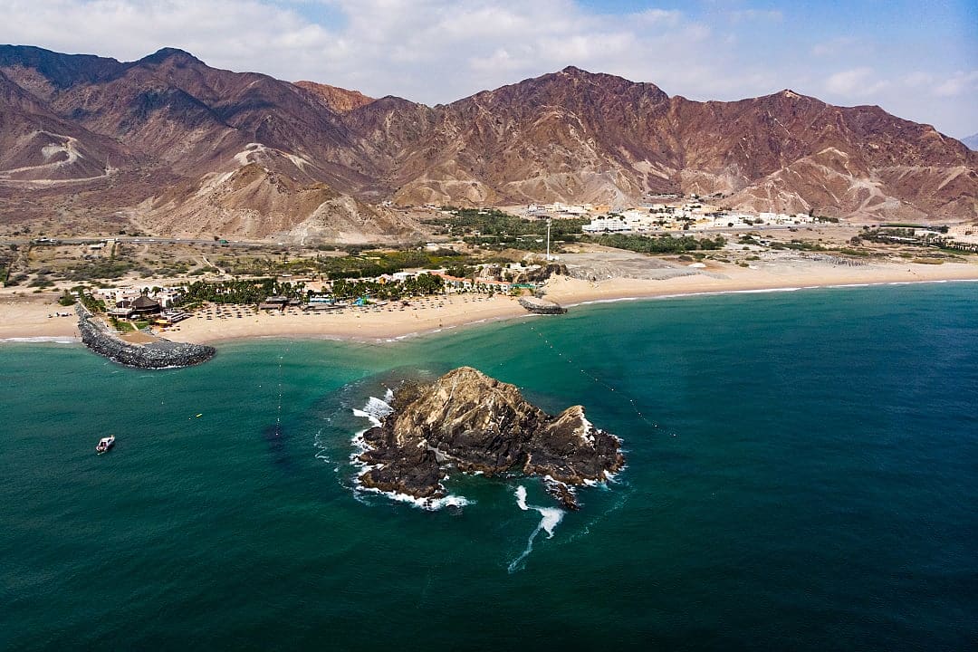 Aerial view of Snoopy Island and beach resort in Fujairah, United Arab Emirates with mountains behind