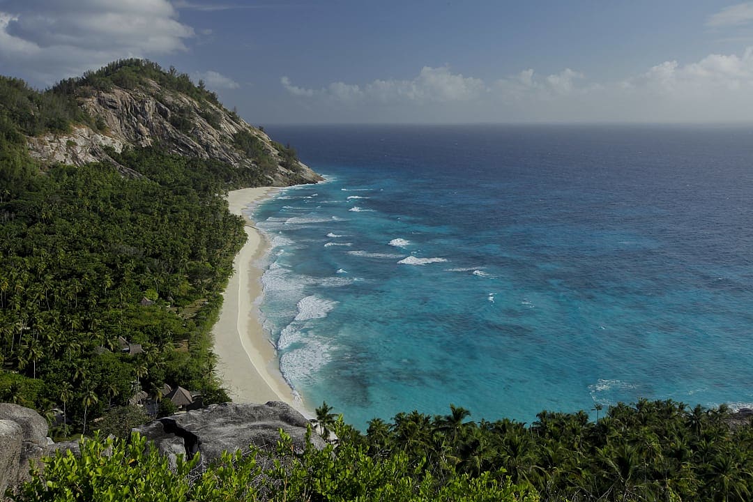 A lush paradise with a tropical beach, where crystal-clear turquoise waters gently lap the shore.