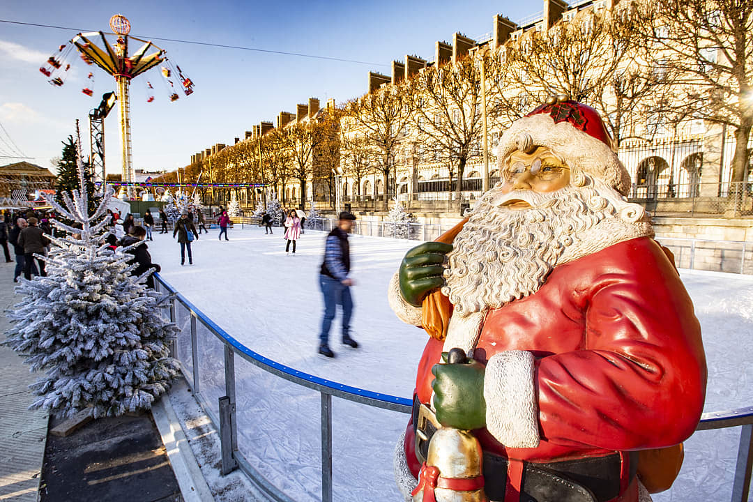 Statue of Santa Claus with people ice skating in the background at the Tuileries Christmas Market in Paris, France